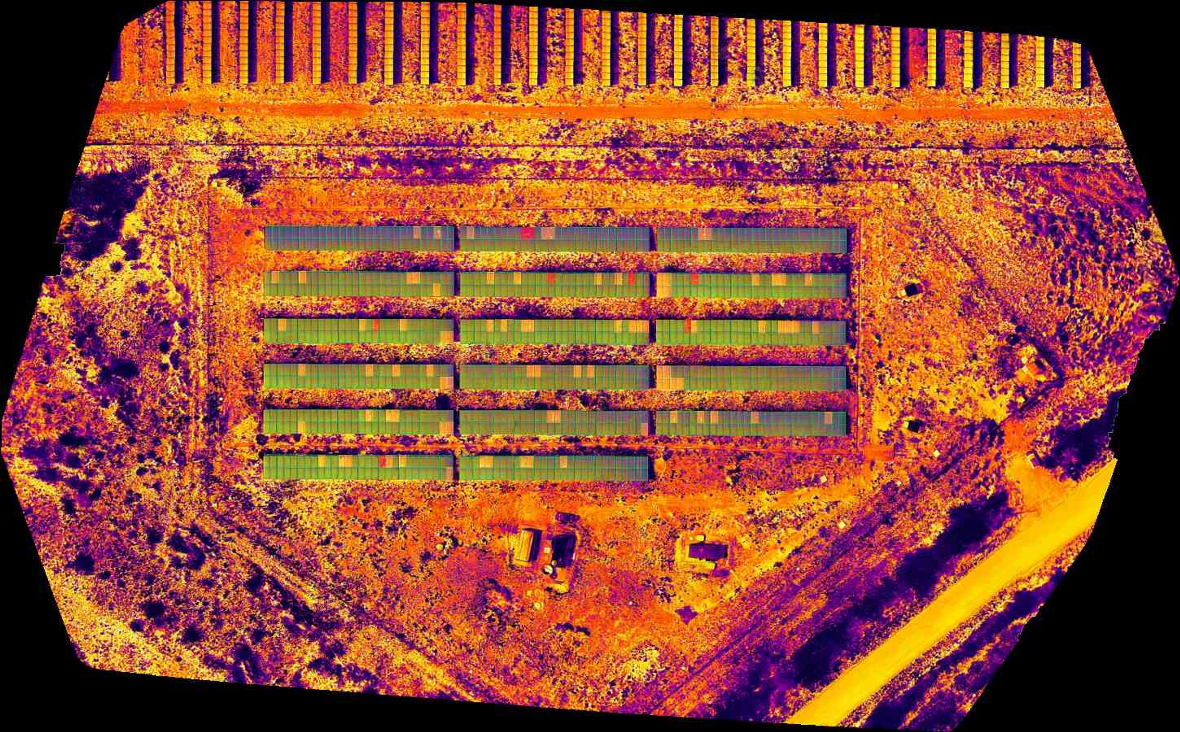 Imagem termografica aerea de usina solar com anomalias destacadas por cores.