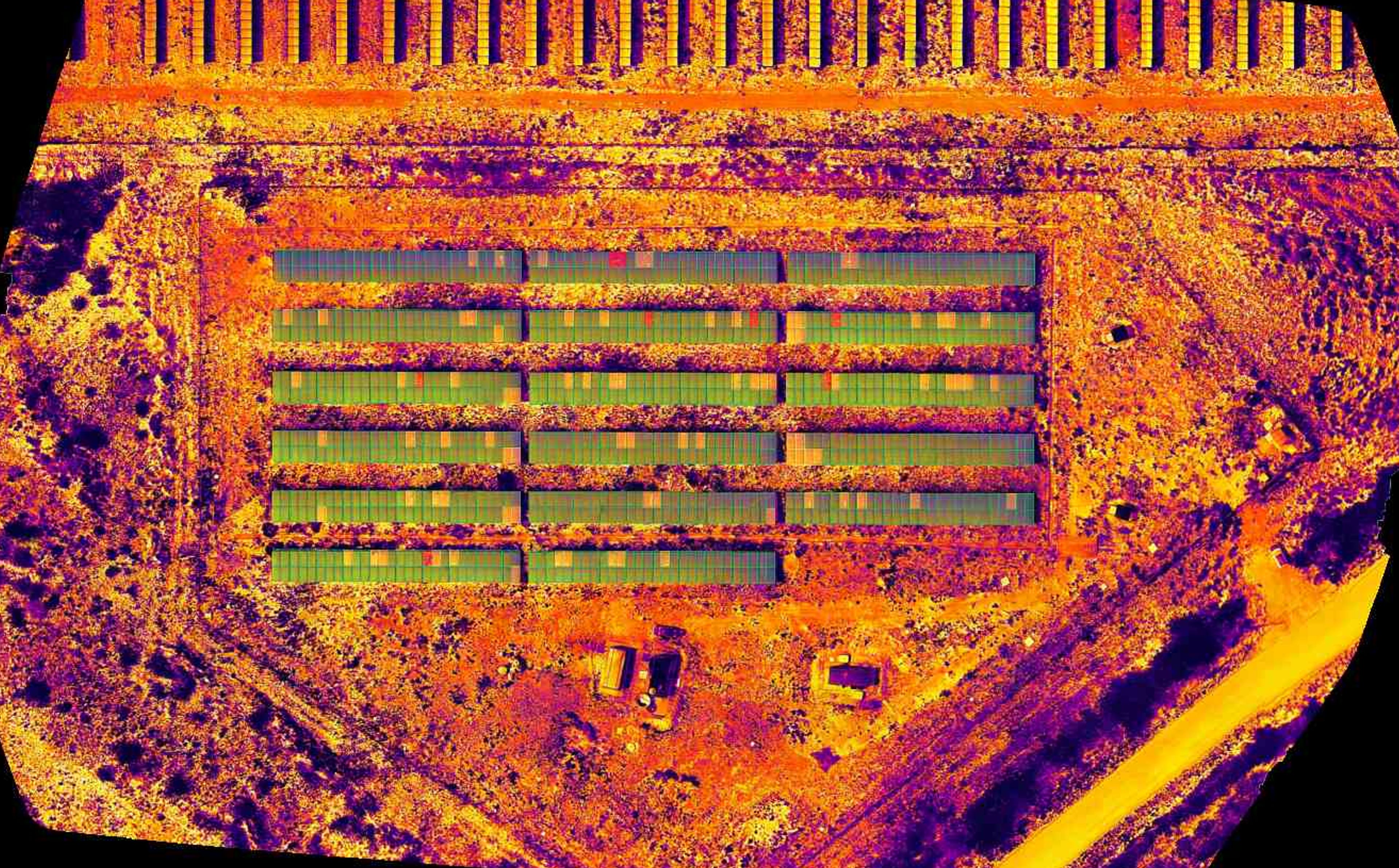 Imagem termografica aerea de usina solar com anomalias destacadas por cores.