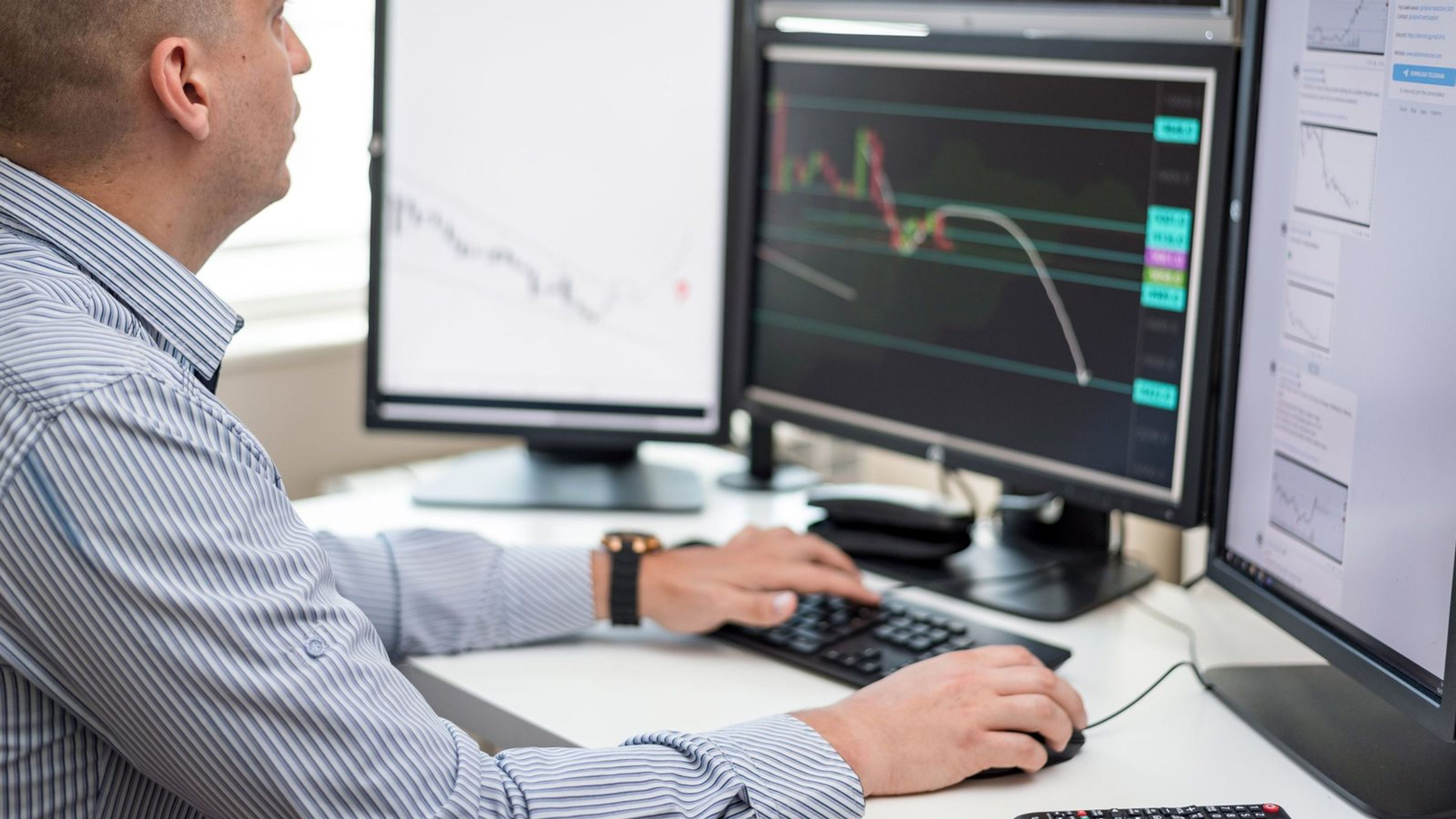Analista examinando gráficos de dados em vários monitores.