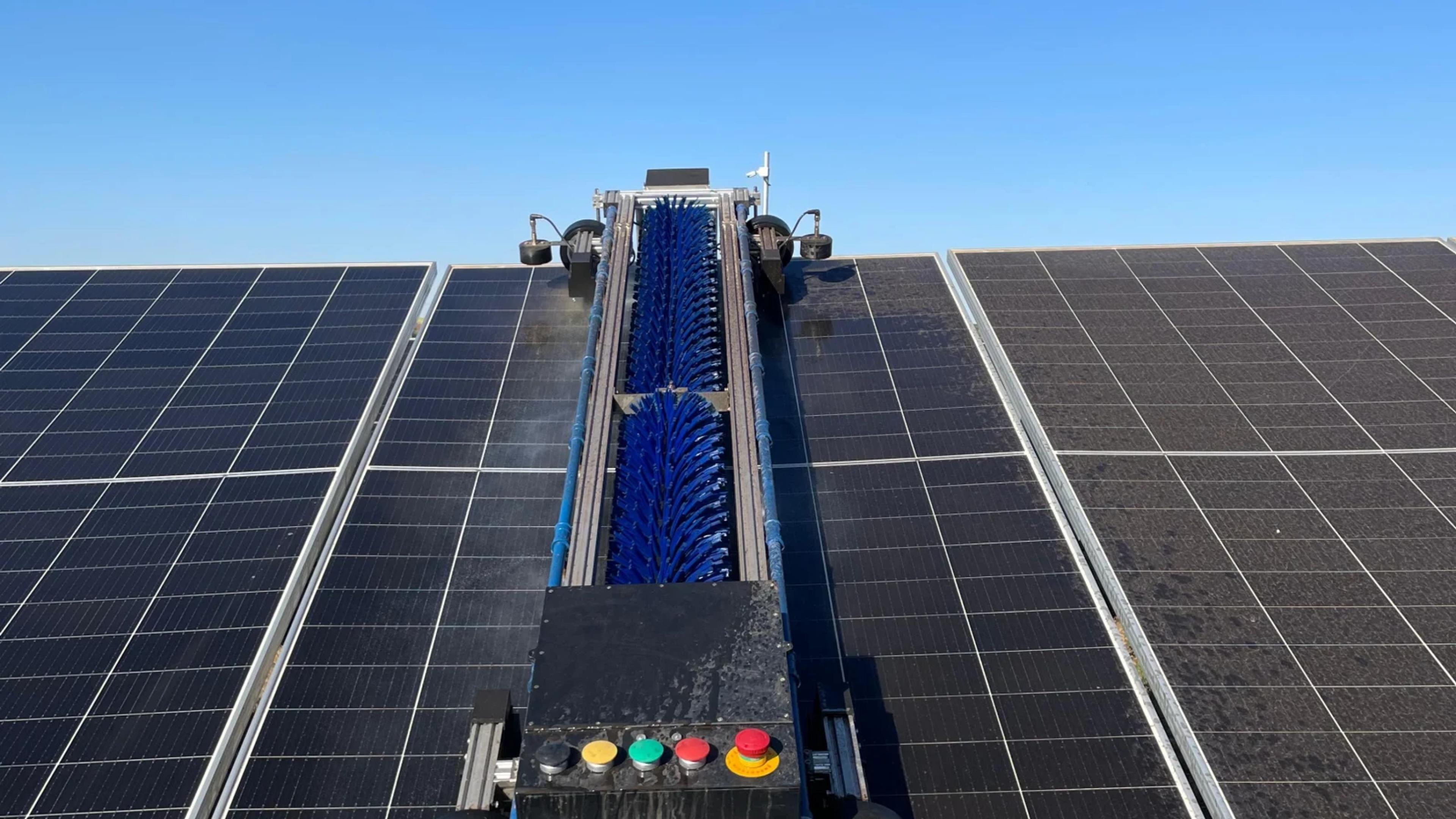 Robo TCR-W1 com escova em operacao sobre fileira de modulos fotovoltaicos.