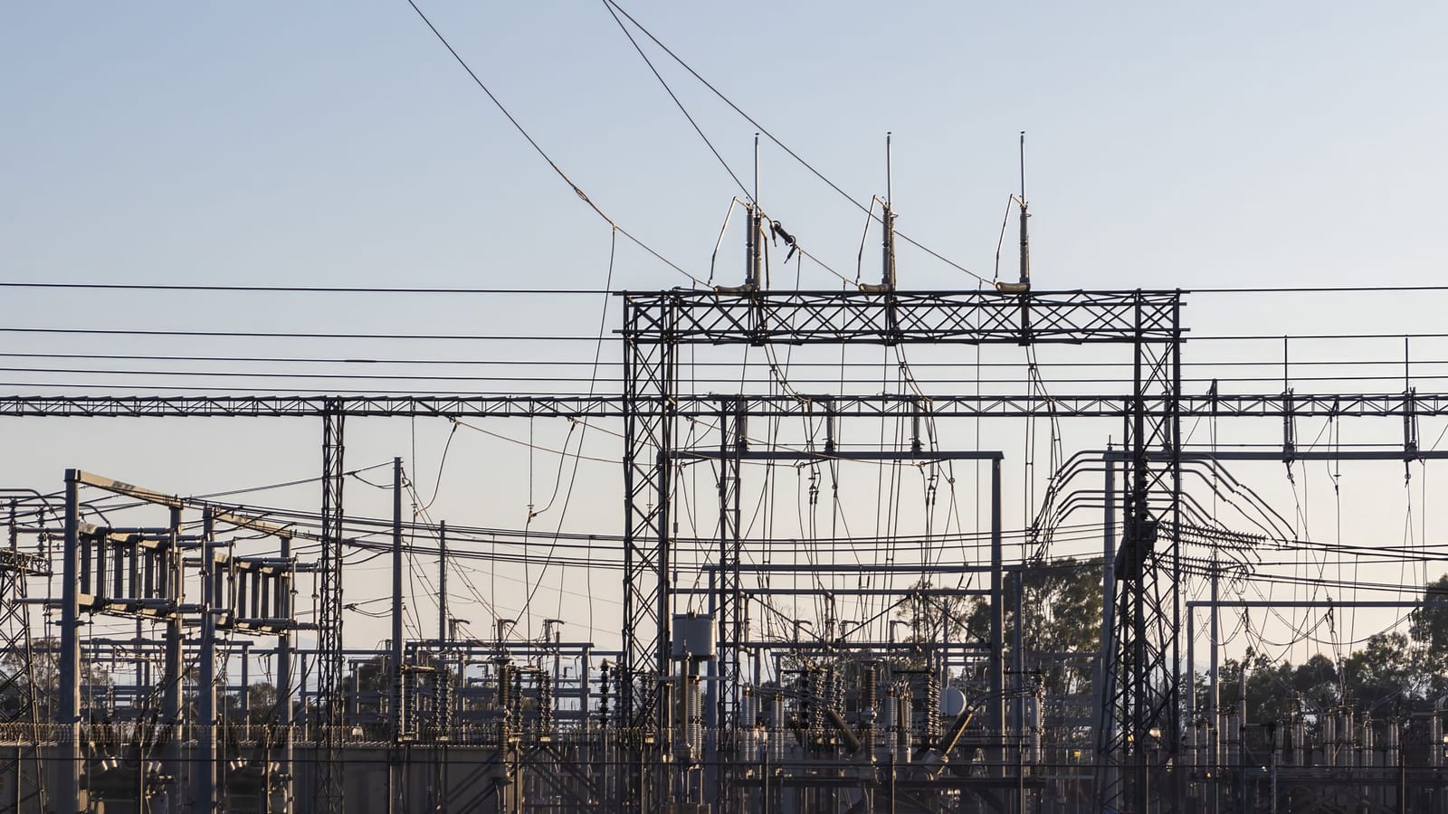 Subestação elétrica com linhas de transmissão ao entardecer.