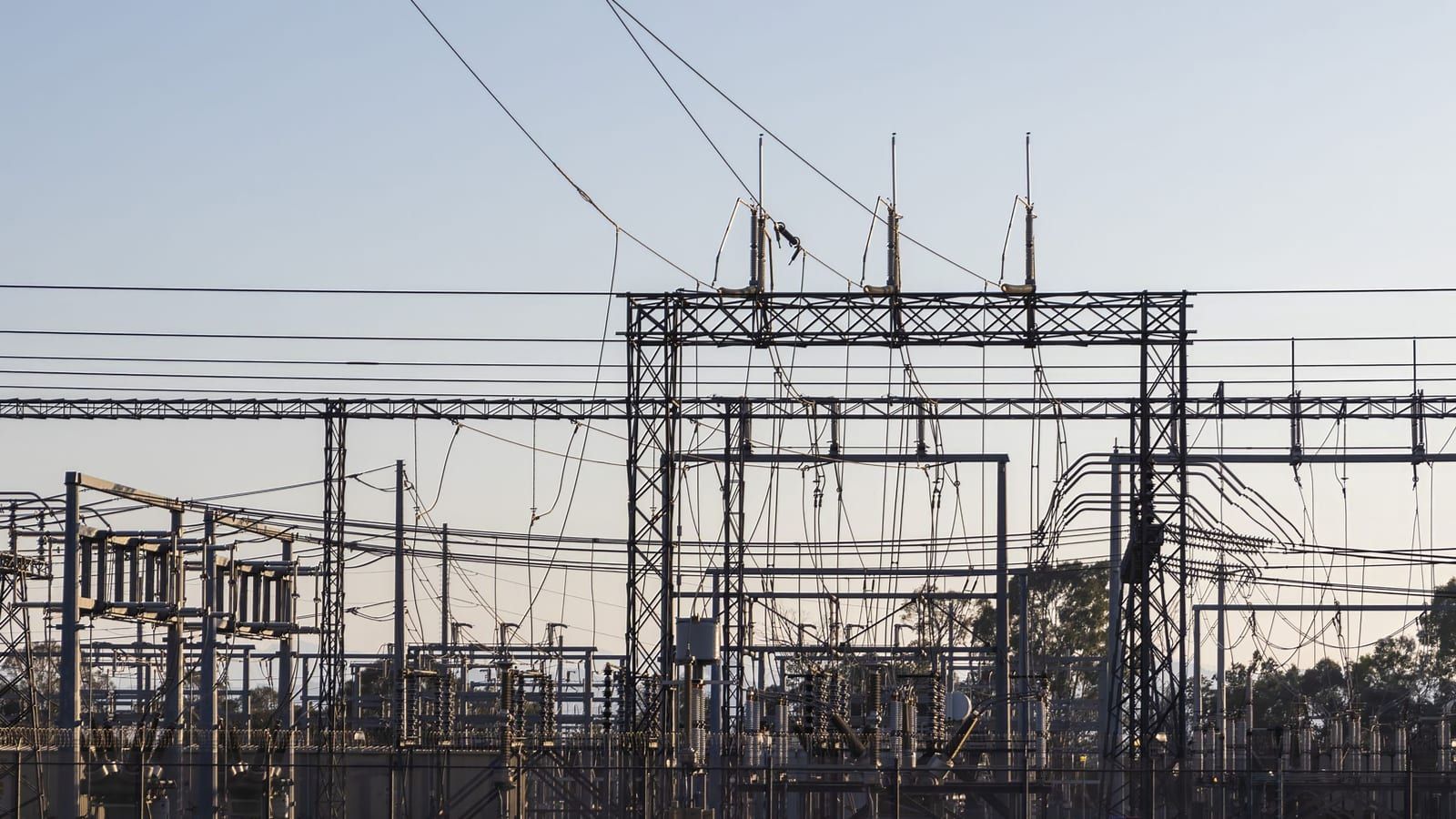 Subestação elétrica com linhas de transmissão ao entardecer.