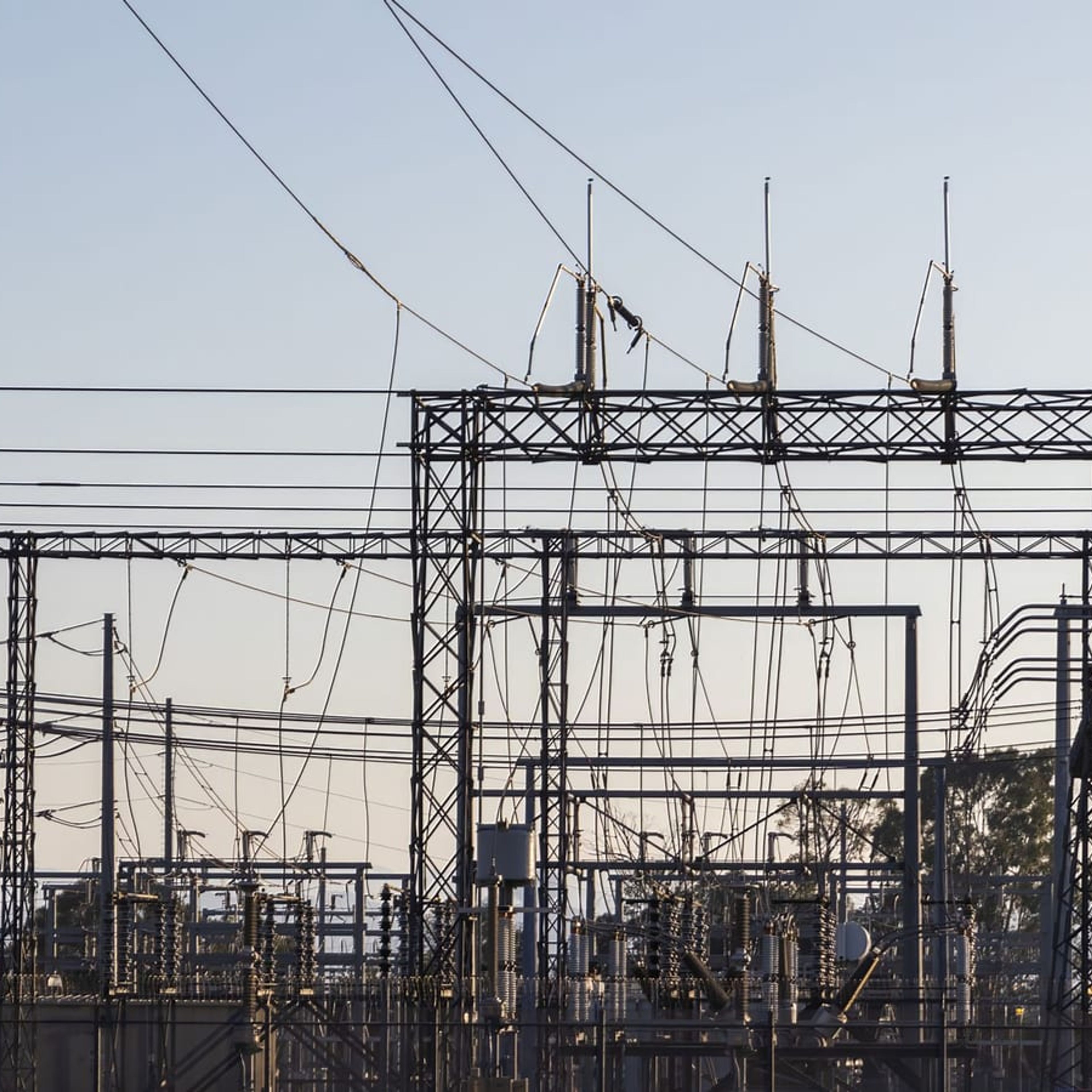 Subestação elétrica com linhas de transmissão ao entardecer.