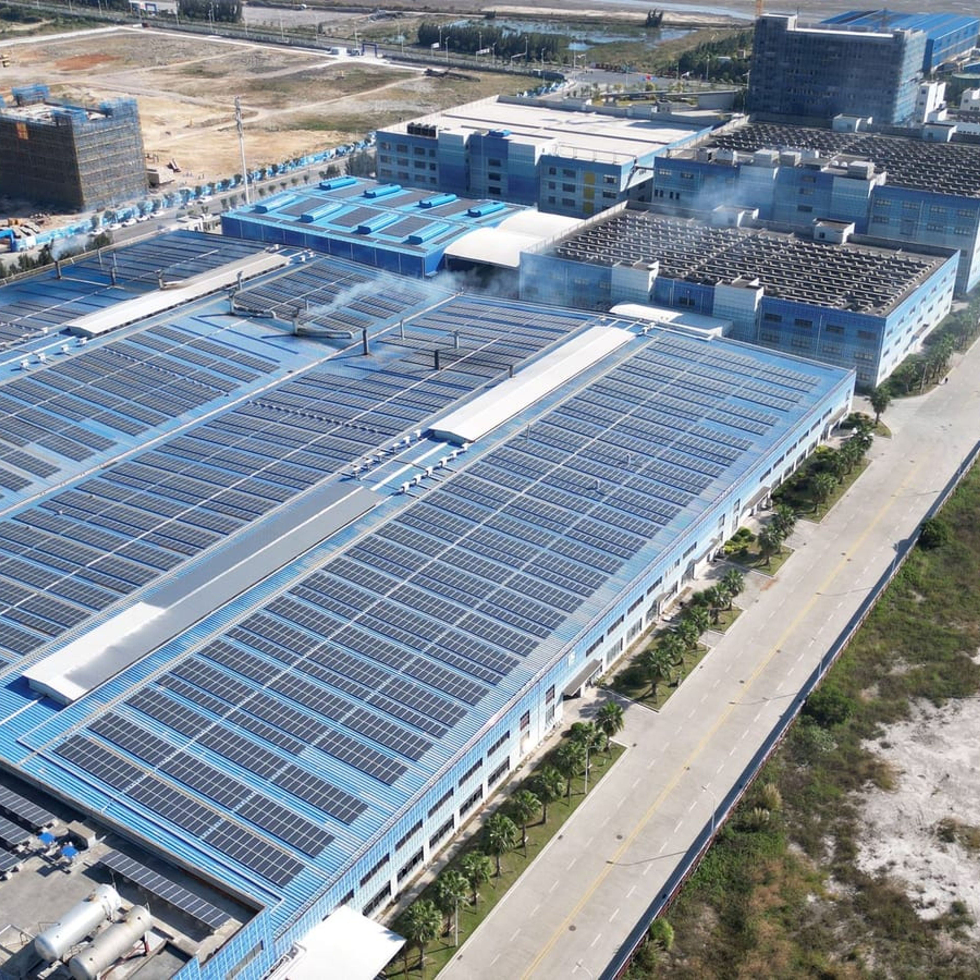 Vista aérea de complexo industrial com módulos fotovoltaicos na cobertura.