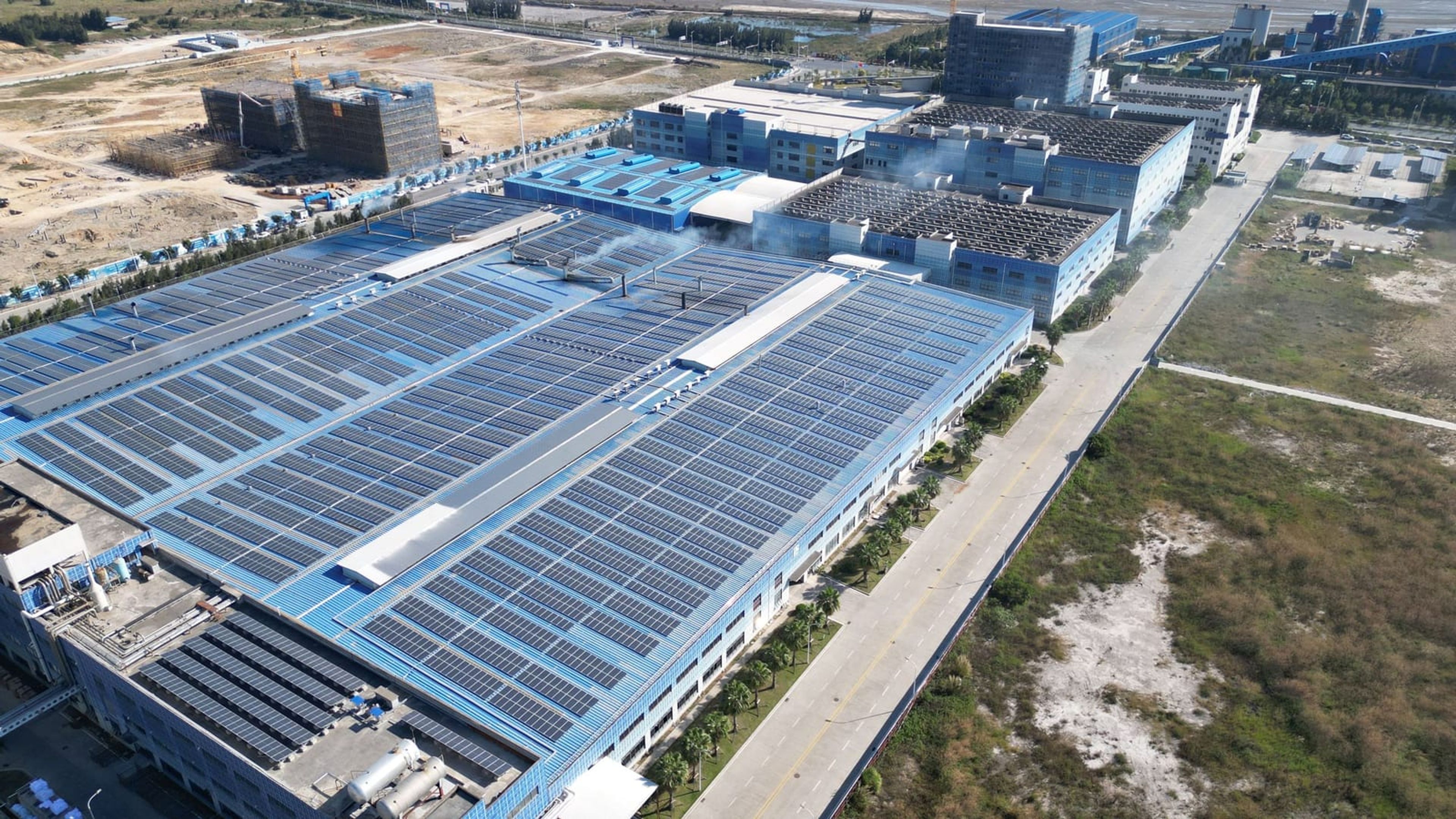 Vista aérea de complexo industrial com módulos fotovoltaicos na cobertura.