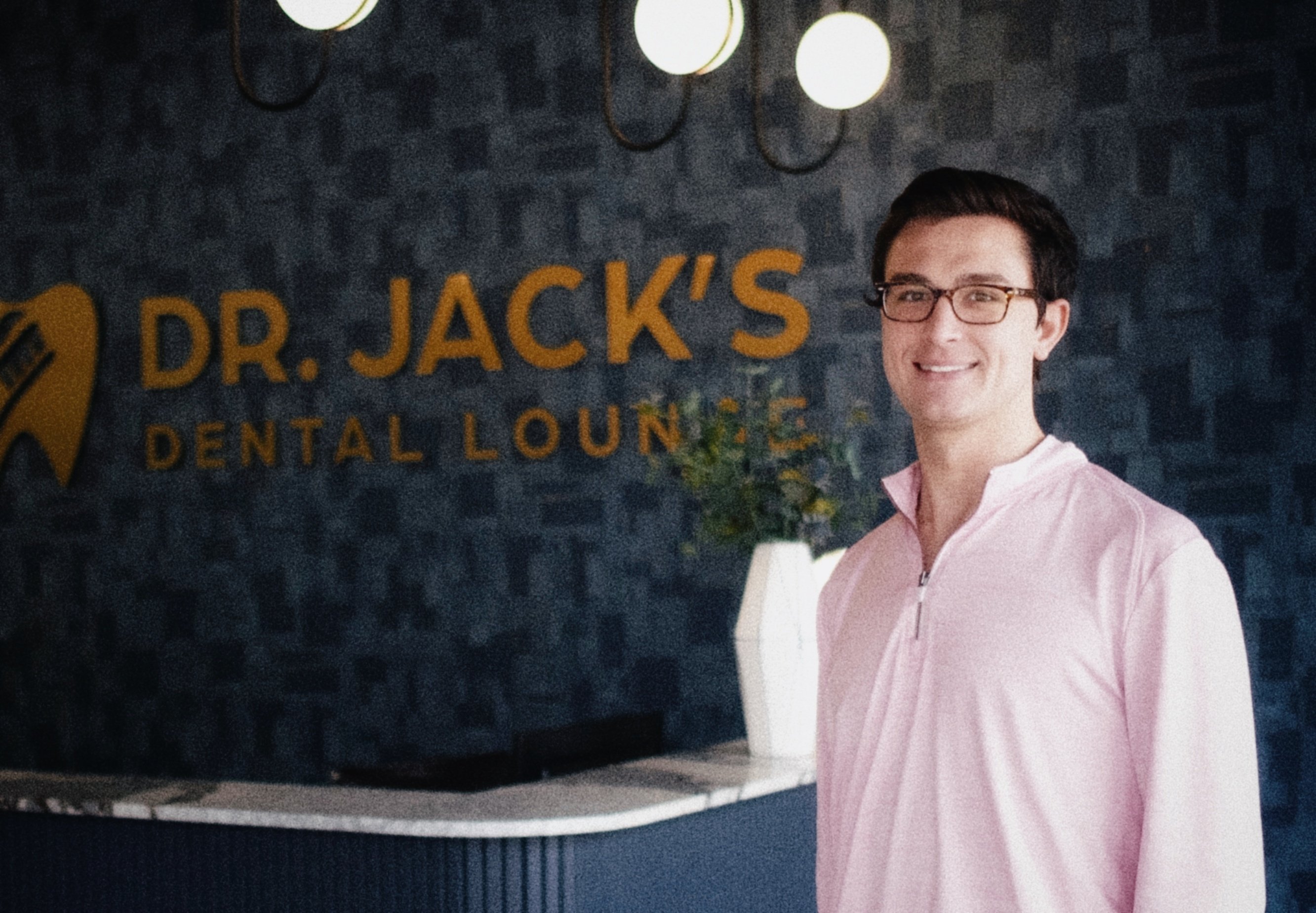 Dr. Jack Geissler standing in front of the Dr. Jack's Dental Lounge signage