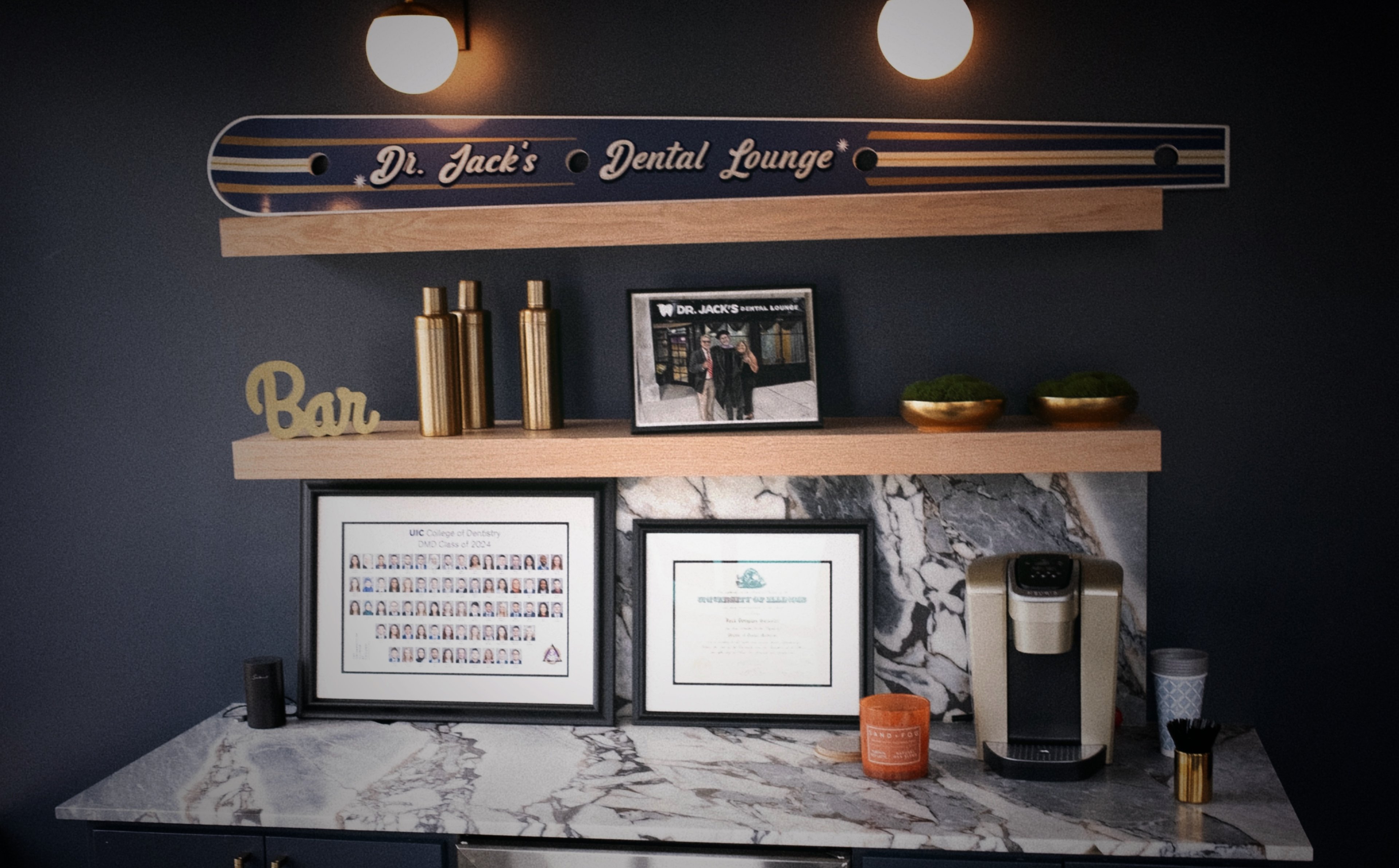 The shelf at Dr. Jack's Dental Lounge, with a hand-lettered shotski, brass thermoses, and a watercolor of Jack in graduation regalia