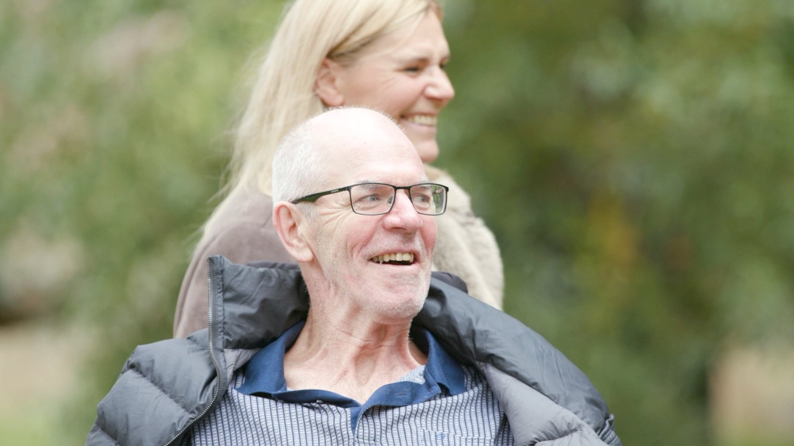 A Synchron trial participant smiling outdoors with his wife.