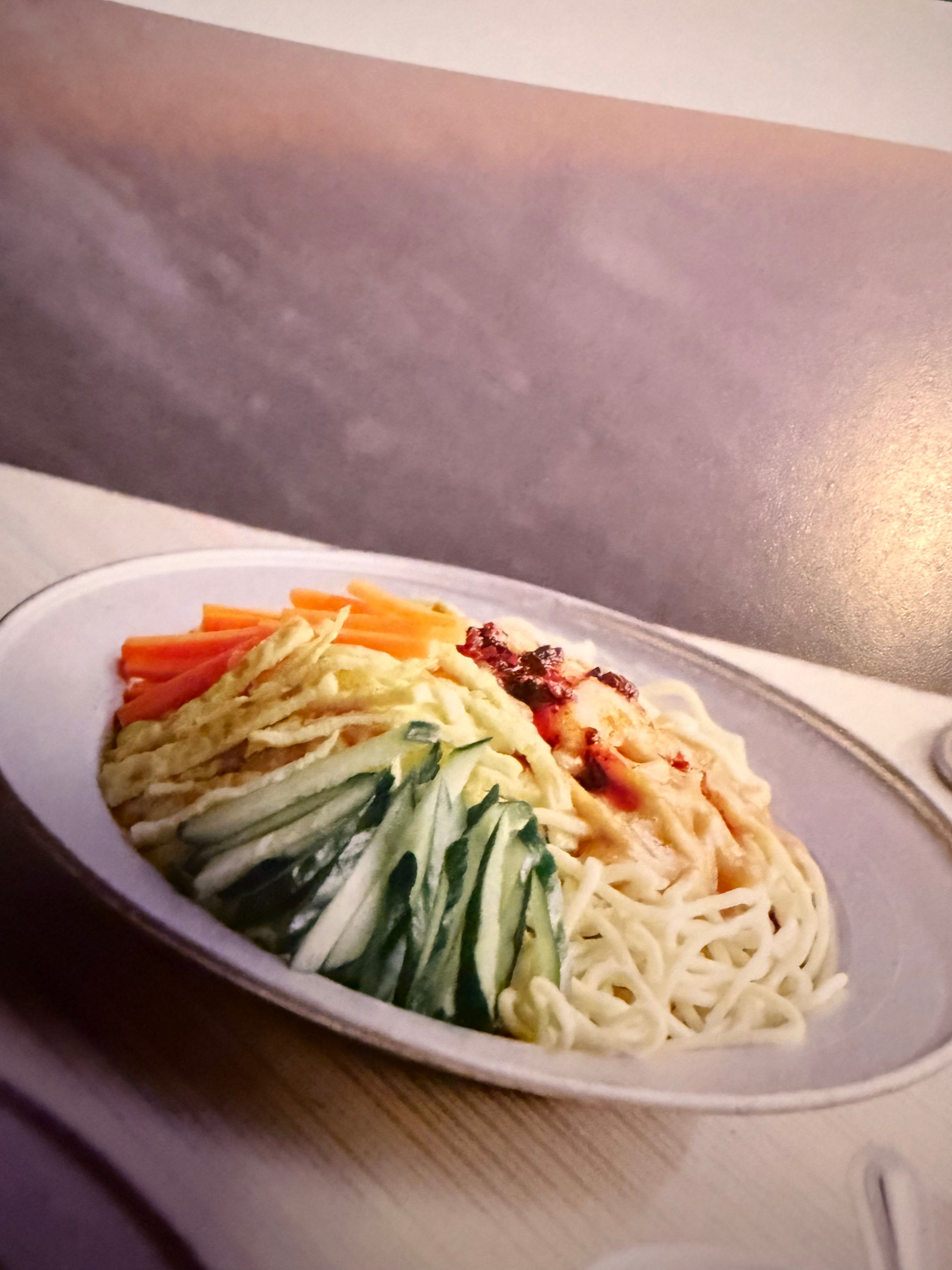 plate of noodles covered with egg, cucumber and carrot
