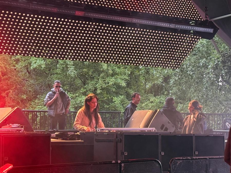 dj behind dj set with trees behind