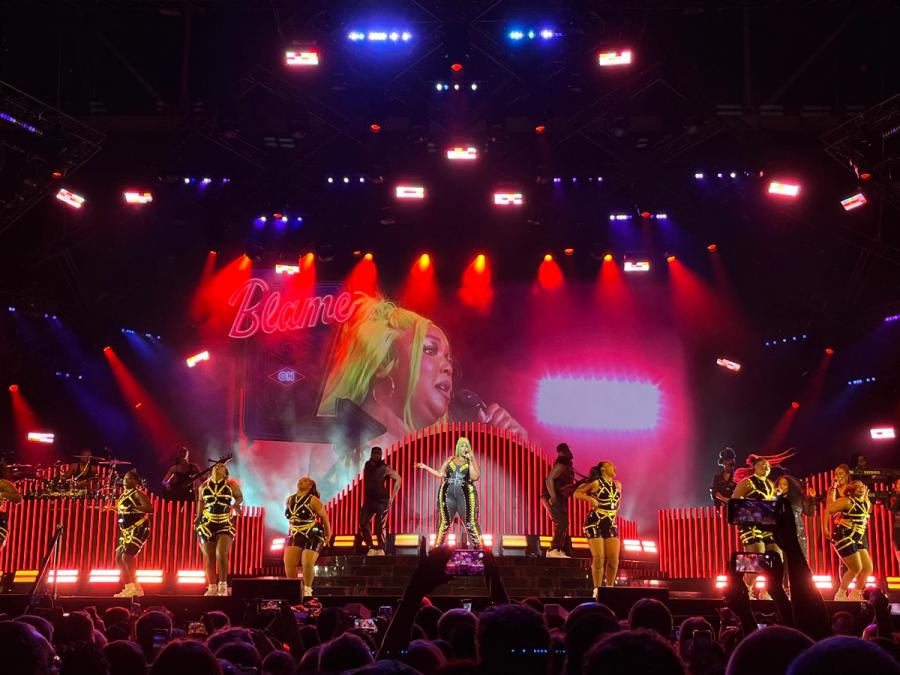 Lizzo in the center of the stage surrounded by female dancers and band 