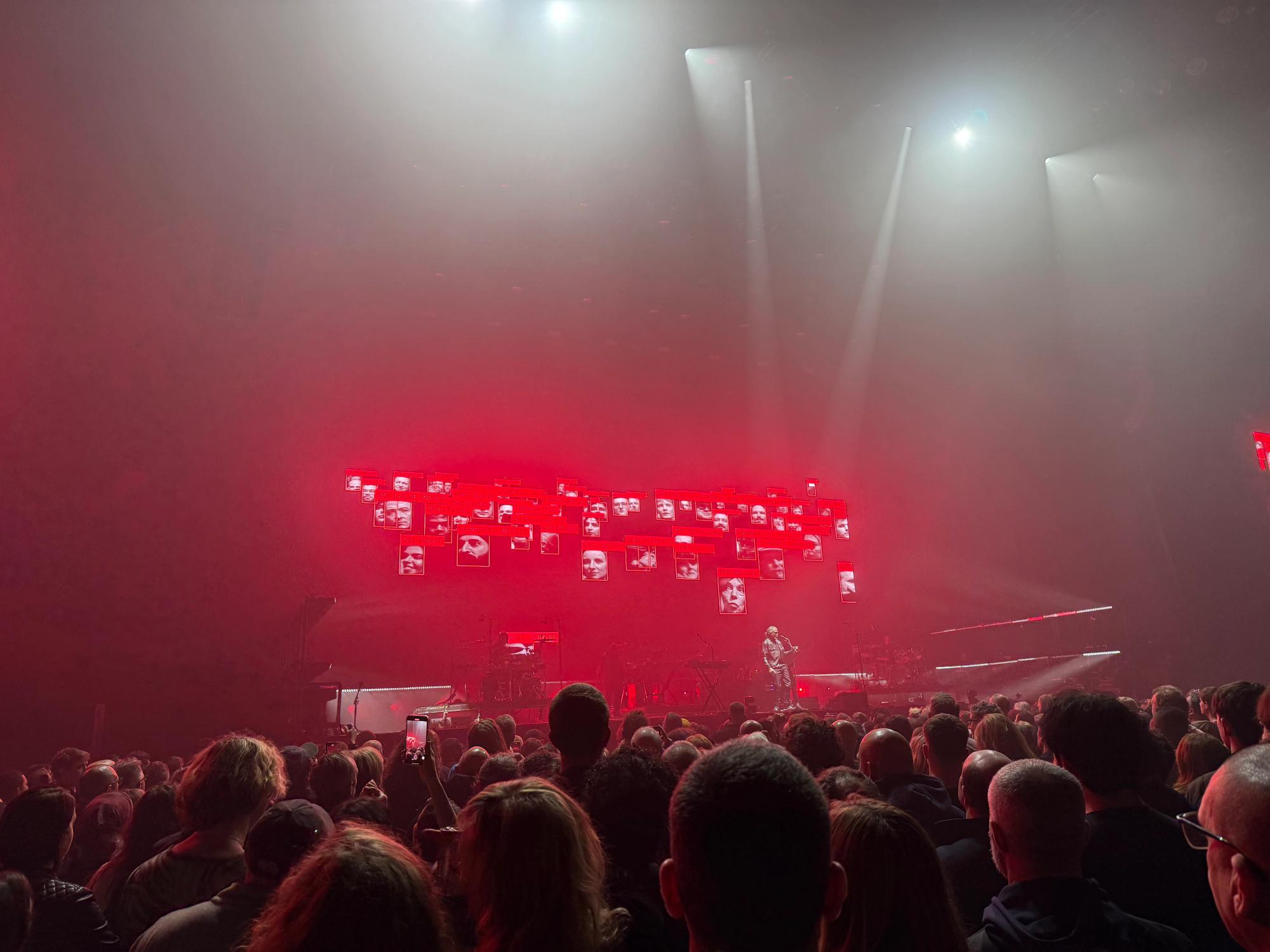 Horace Andy singing, behind are pictures of people with AI-like identification that shows their characteristics, like ambitious, influential and decisive