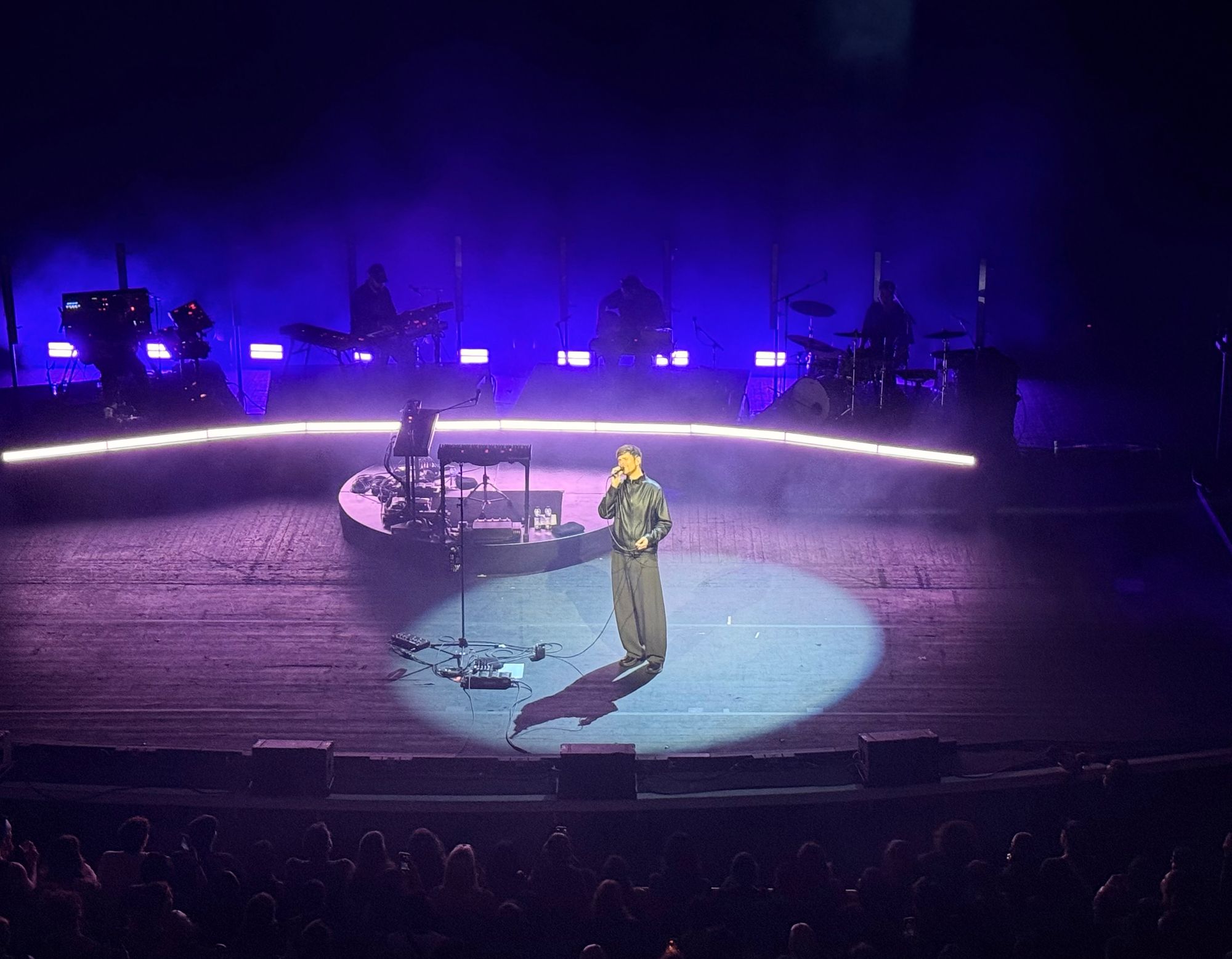 James singing holding a mic with four piece band in background