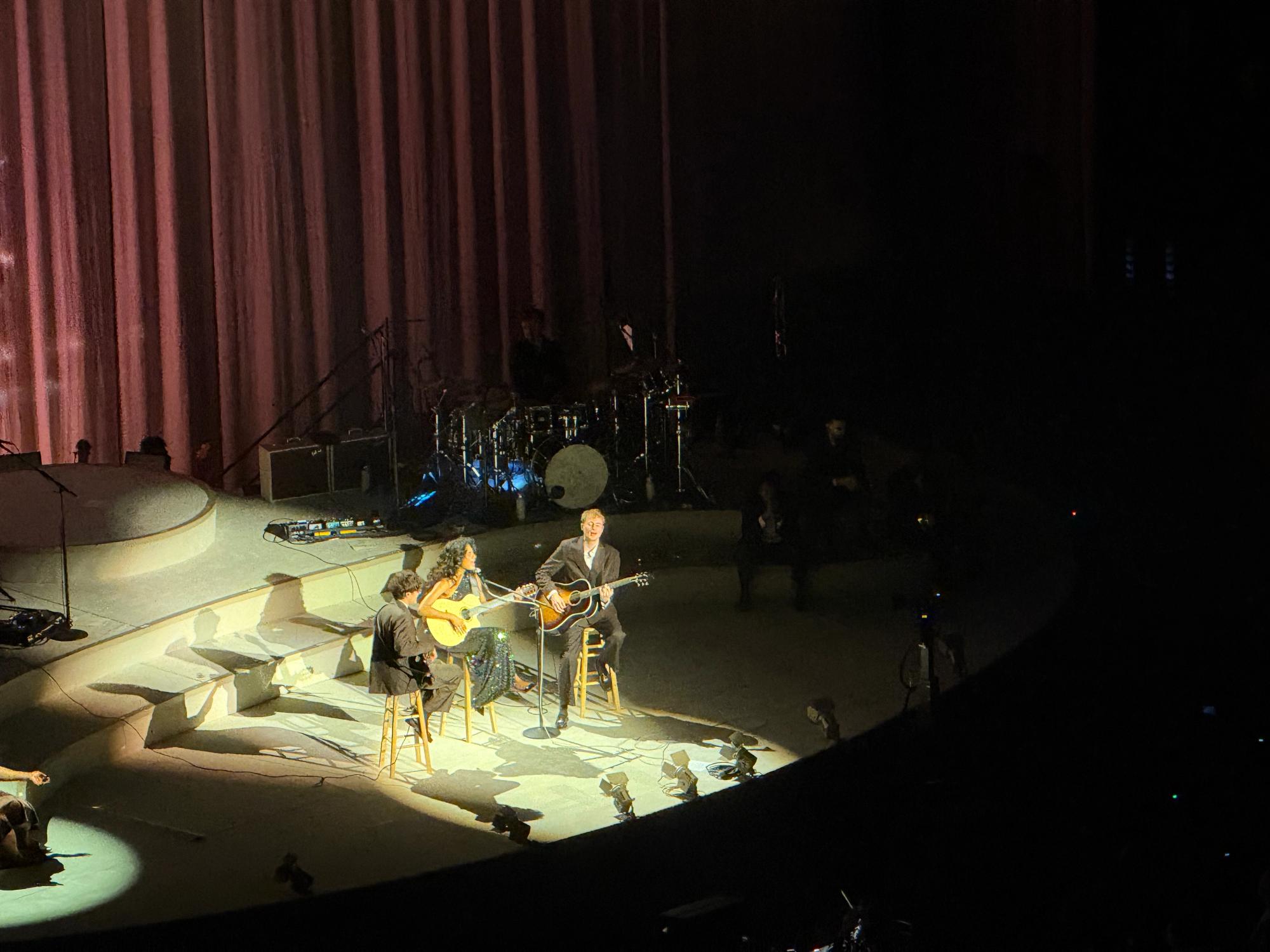 olivia seated on stage holding guitar and singing