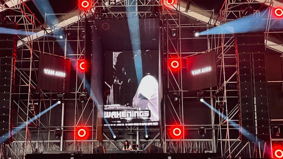 circular red neon lights around a stage, female DJ is on stage, the name Van Anh is displayed on two screens on the side in white capital letters