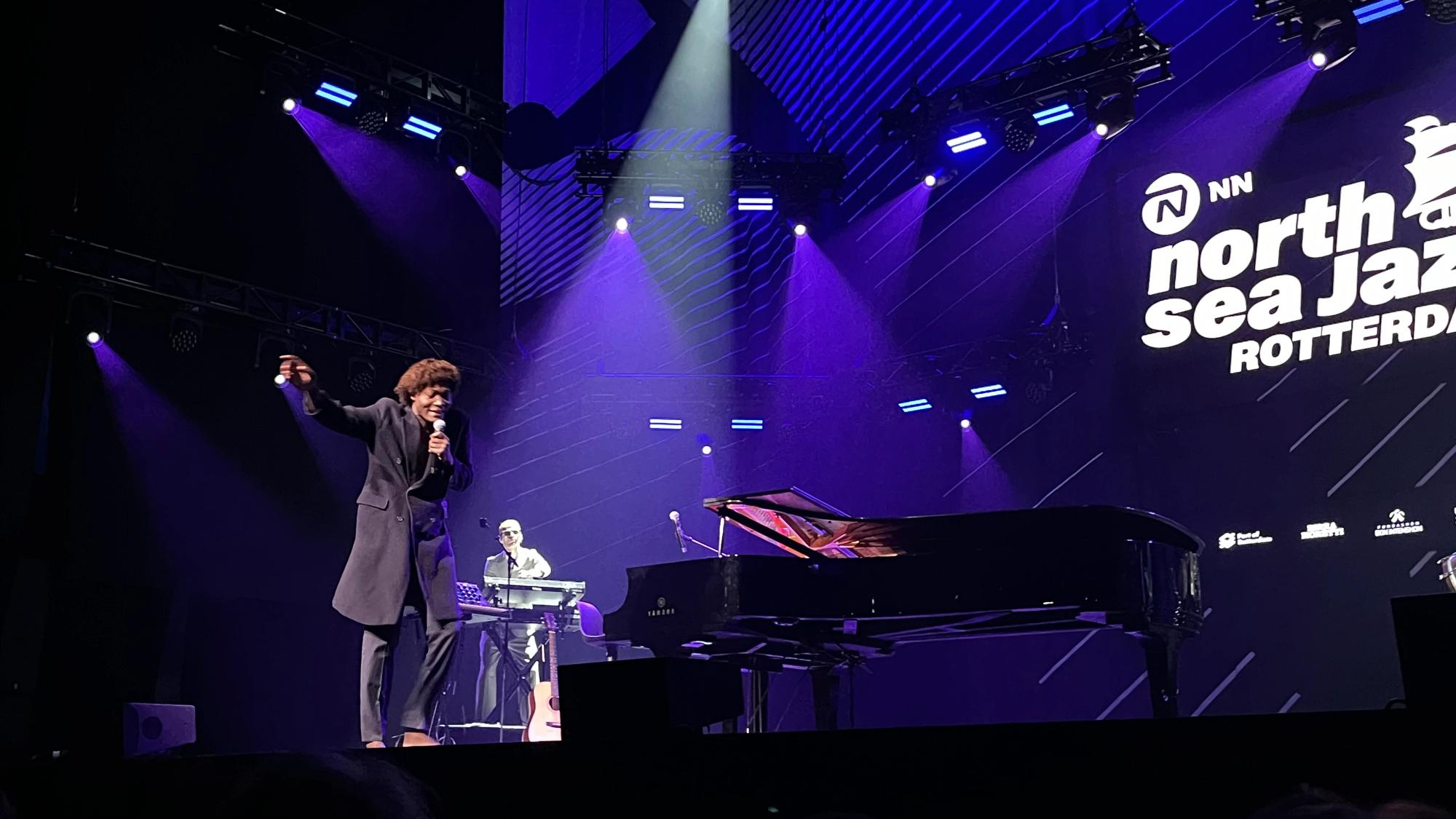 Benjamin in suit standing next to grand piani