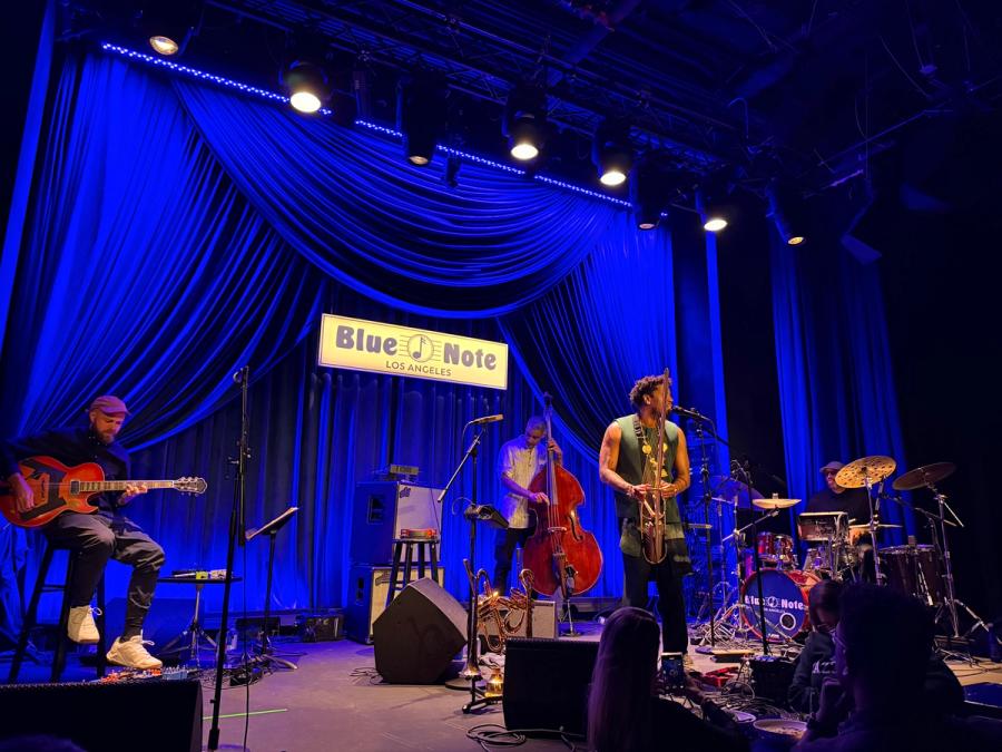 whole band on stage with blue note LA logo in the back