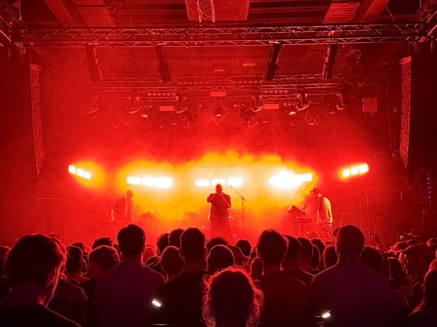 Sef in middle with crowd watching, red stage lights make the whole picture red ish