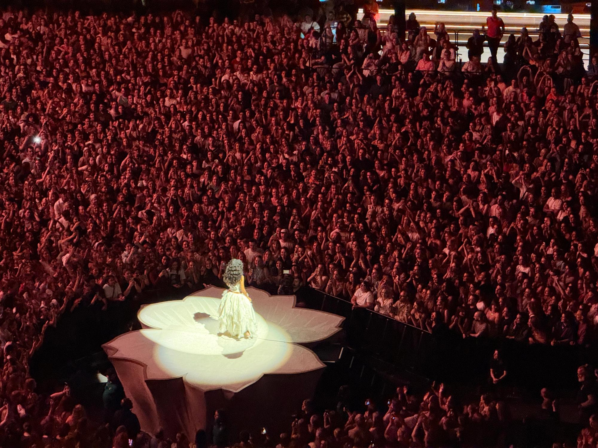 Olivia in a white dress in a circle surrounded by huge crowd