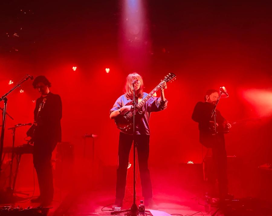 Roos Rebergen in red lights, guitarists left and right