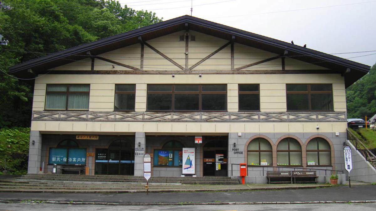 層雲峽巴士總站的建築正面,一樓有道北巴士案內所與郵局,背後是峽谷的綠色山壁