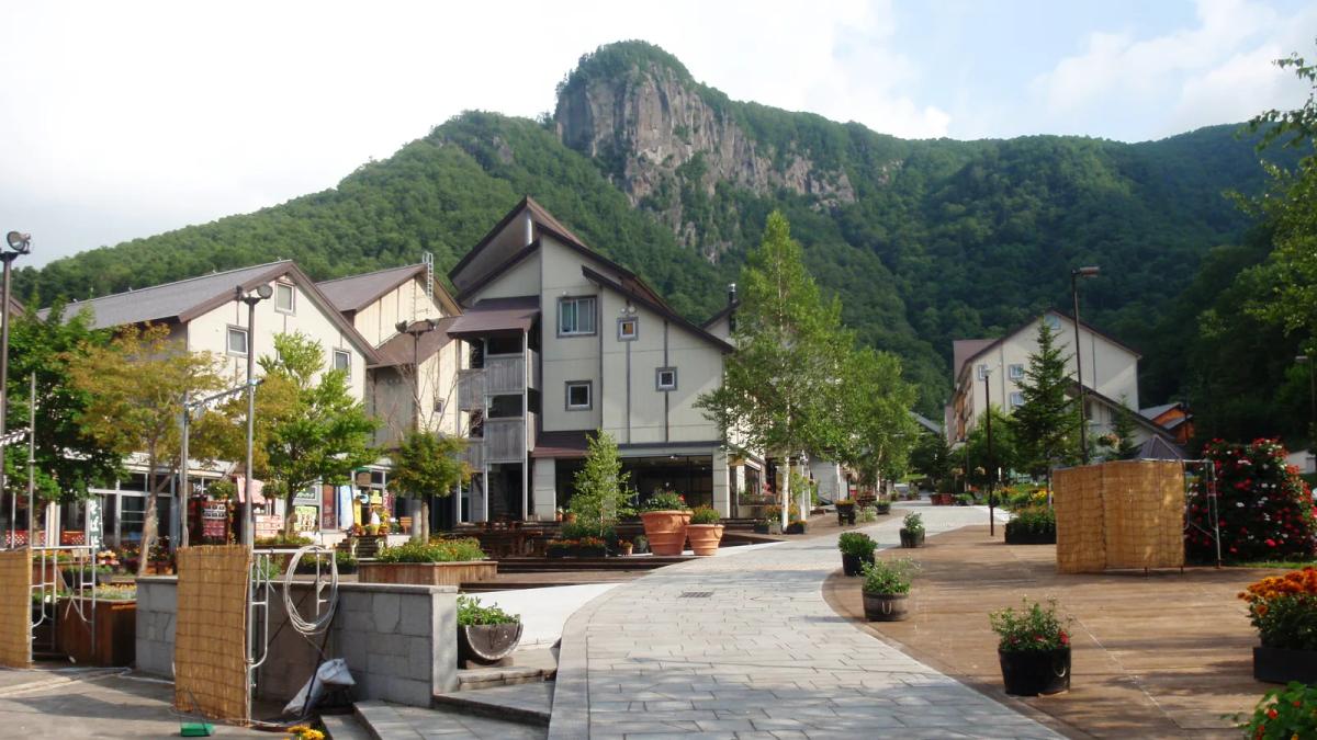 層雲峽溫泉街的石板步道，兩旁是三角屋頂的建築，後方是長滿樹的岩峰