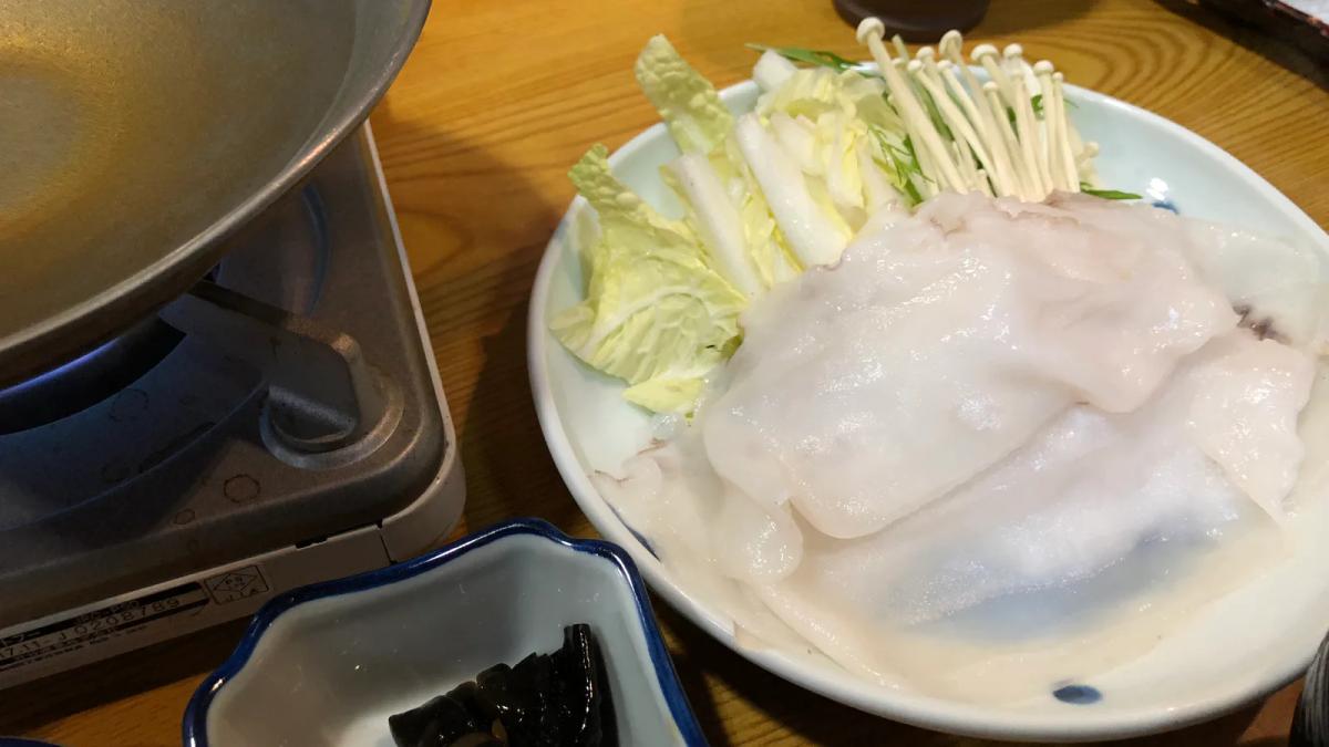 稚內的章魚涮涮鍋，盤子上鋪著切成薄片的白色水章魚，旁邊有白菜、金針菇與爐上的鍋