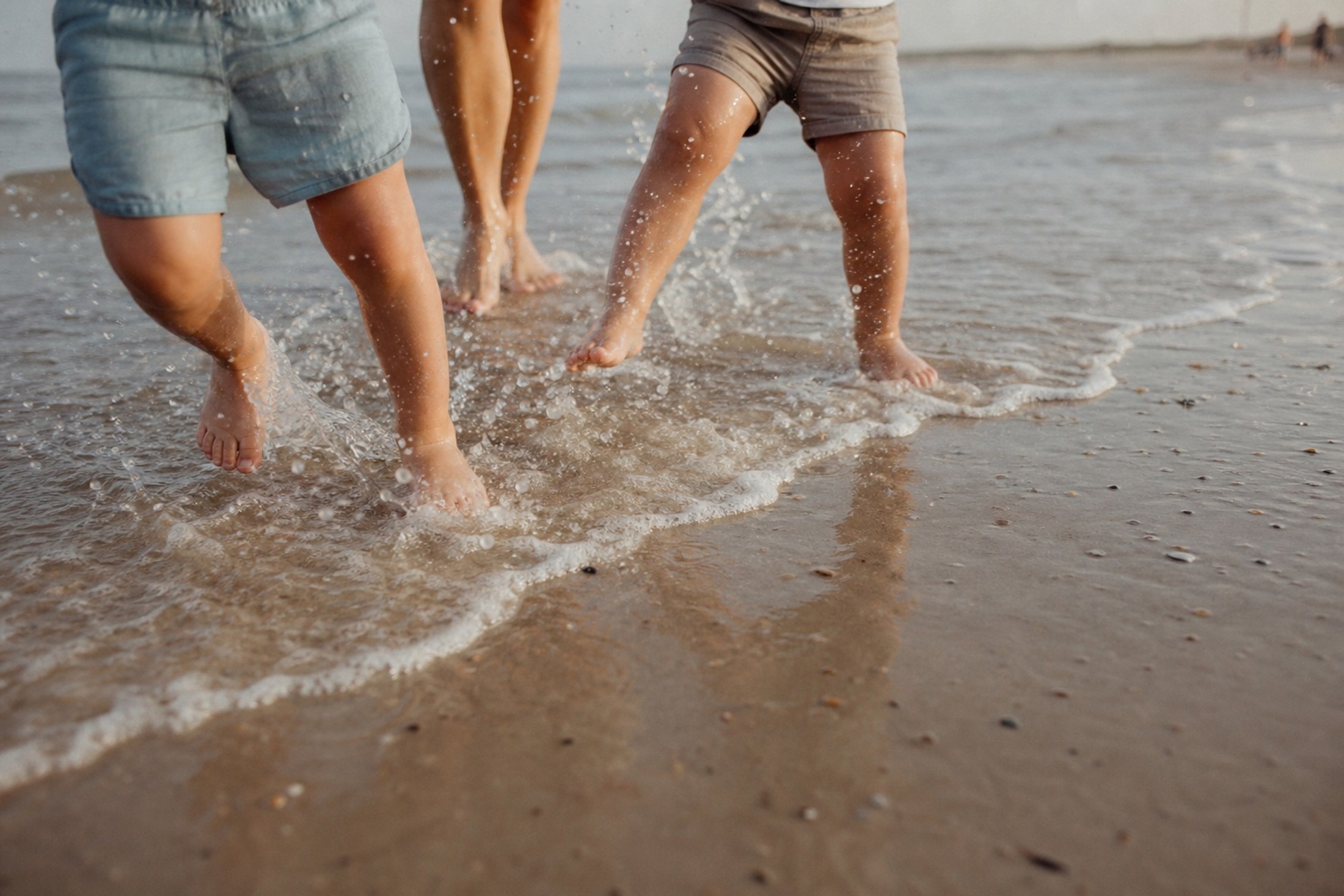 Kindervoeten spetteren door de vloedlijn aan zee
