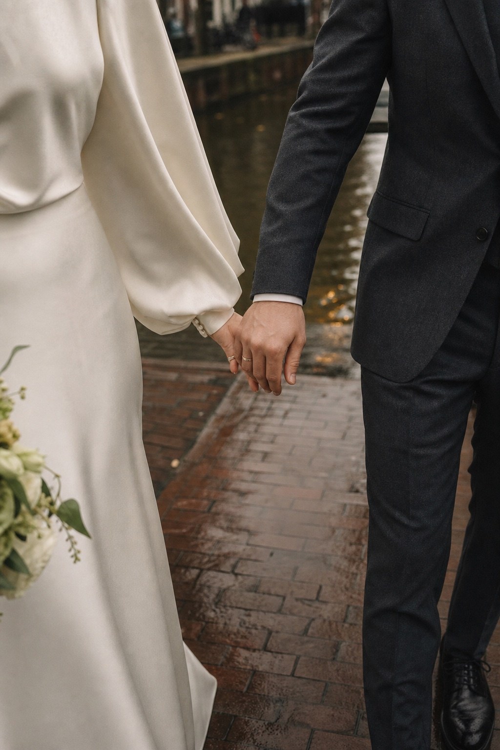Handen van een pasgetrouwd stel langs een Amsterdamse gracht