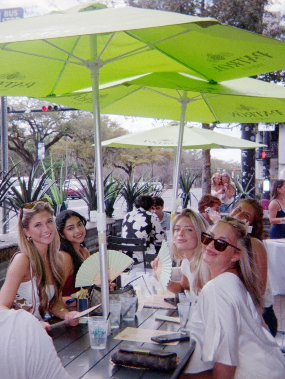 Guests at a sunlit patio table under Patrón umbrellas at Cantina Añejo brunch
