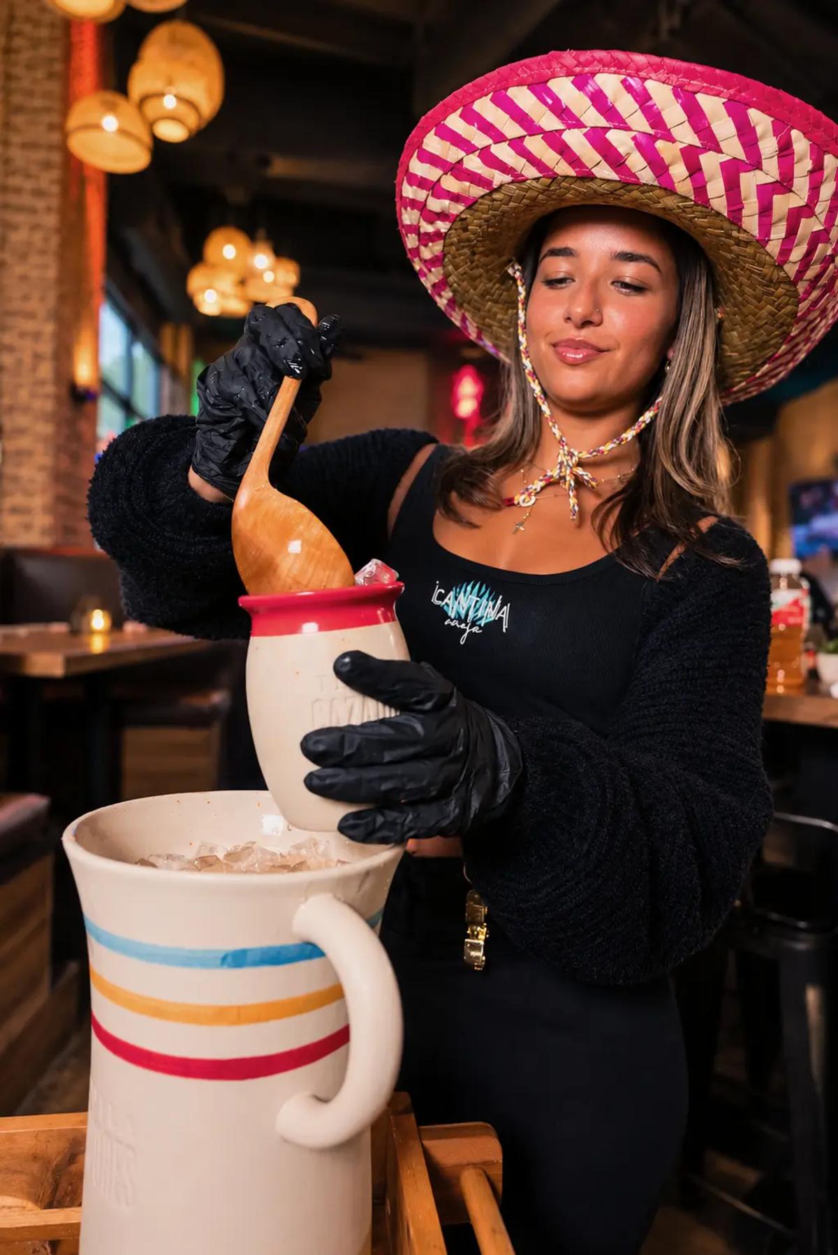 A Cantina Añejo bartender in a sombrero pouring a cantarito tableside