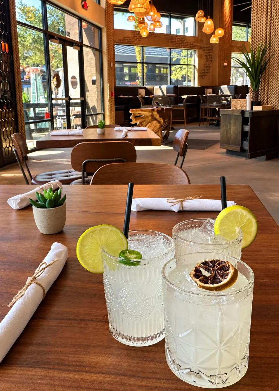 Three margaritas with lime and a charred orange on a table at Cantina Añejo
