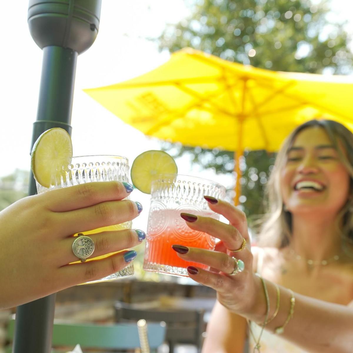 Two guests toasting margaritas on the sunlit patio at Cantina Añejo