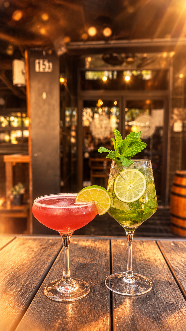 A pink cocktail and a mojito on a wood table at the OAK bar