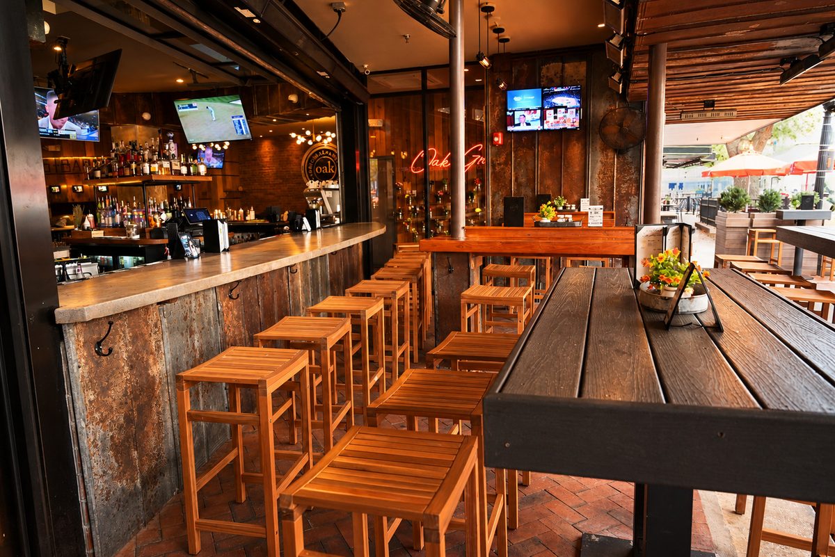 The open-air bar with wooden stools under the new lights