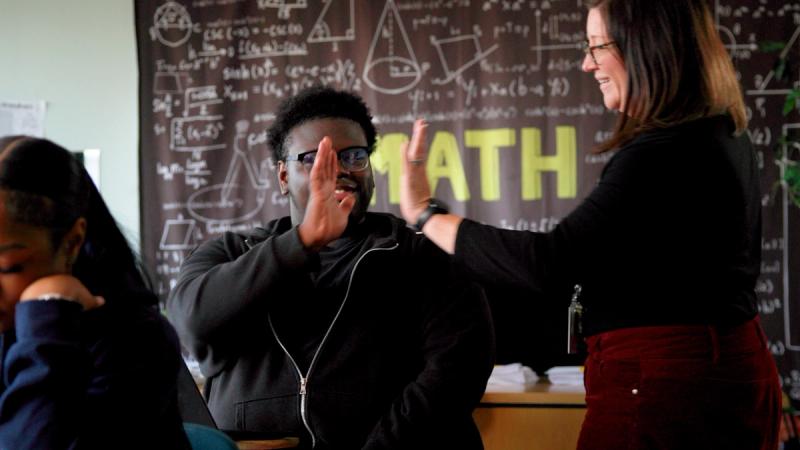 Student and teacher high-fiving in a math classroom at Freire Charter School Wilmington