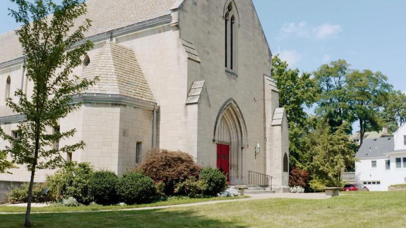 The exterior of St. Paul's Episcopal Church in Mt. Lebanon, Pittsburgh — a stone Gothic-style church with red doors, arched entryway, and landscaped grounds on a sunny day.