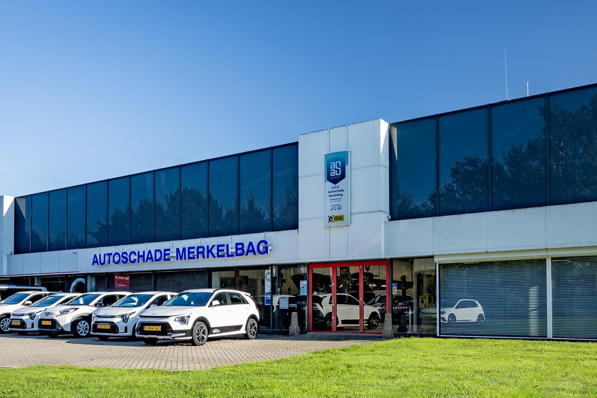 Vooraanzicht van het pand van Autoschade Merkelbag in Maastricht met leenauto's op het voorterrein