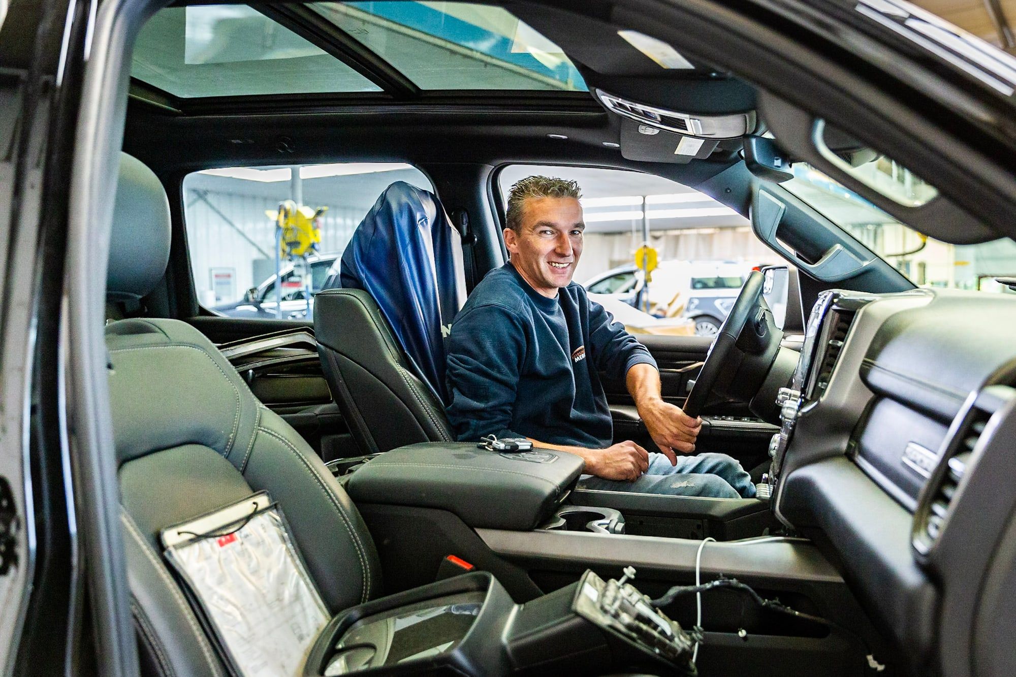 Monteur van Autoschade Merkelbag werkt aan het dashboard en stuur van een auto in de werkplaats