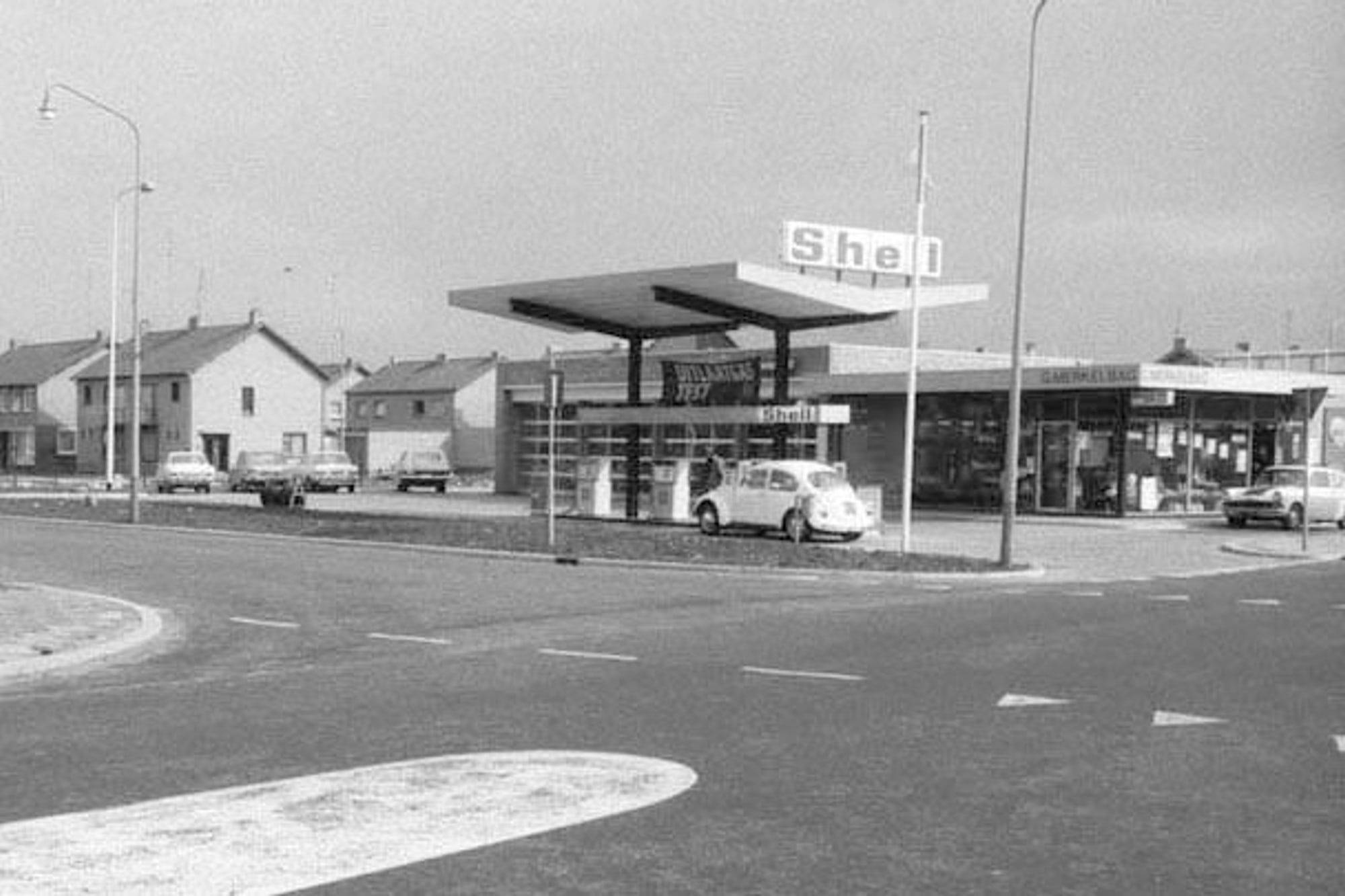 Historische zwart-witfoto van het Shell-tankstation van G. Merkelbag in Maastricht, met een Volkswagen Kever bij de pomp