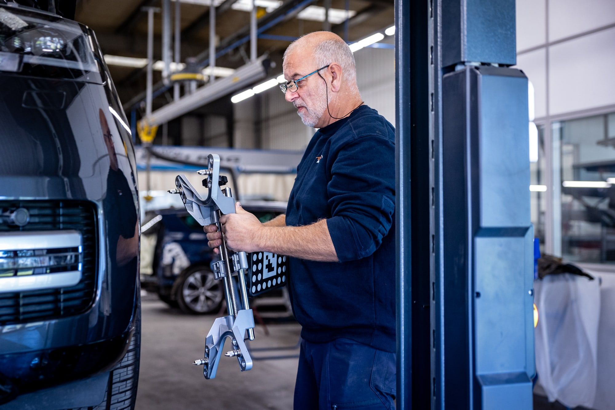 Technicus van Autoschade Merkelbag maakt de kalibratieapparatuur voor rijhulpsystemen gereed in de werkplaats