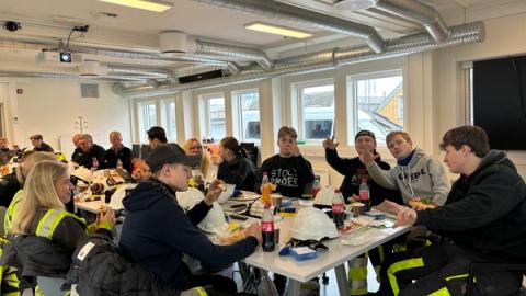 Elever samlet rundt et bord for å spise lunsj.