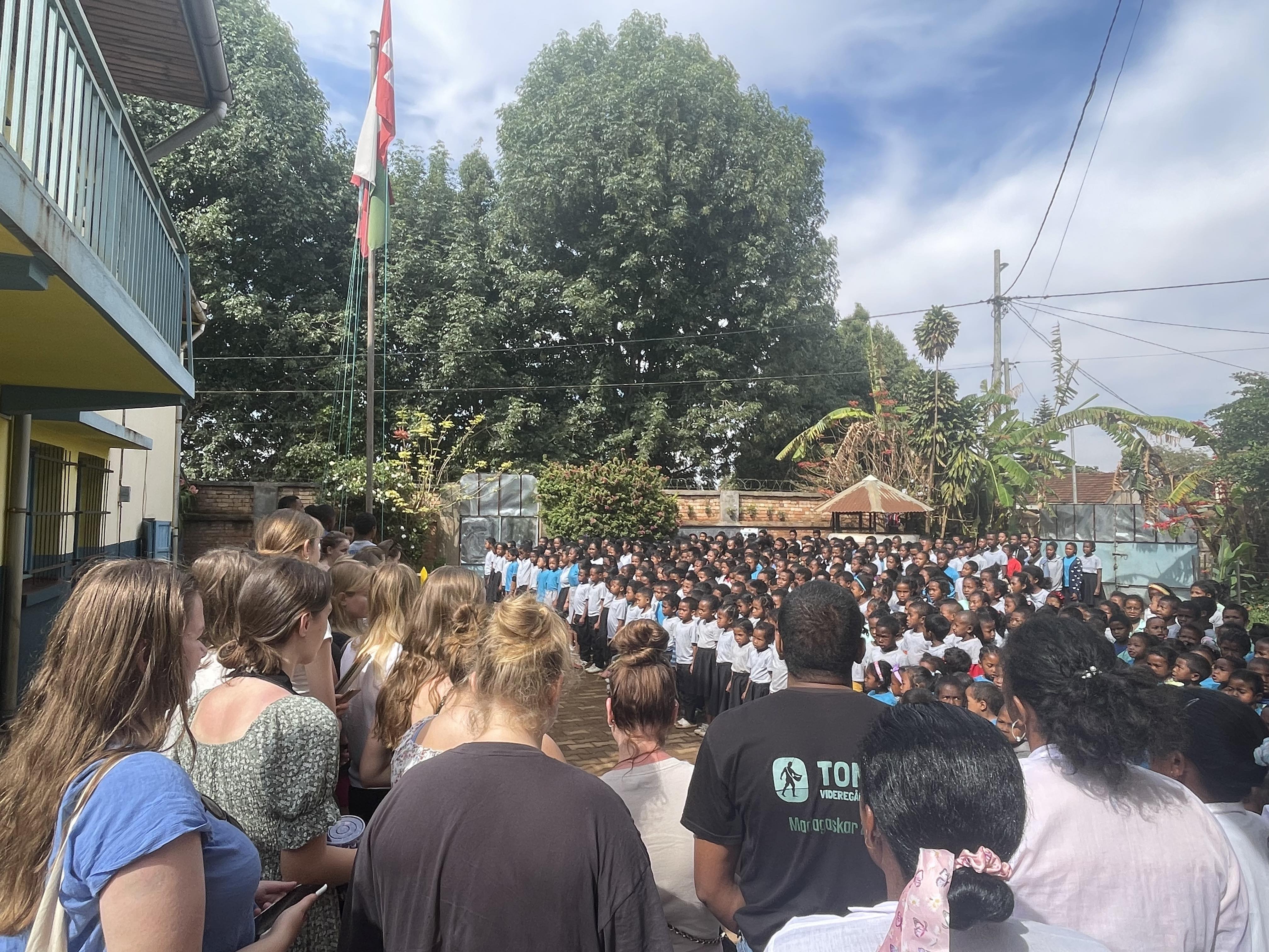 Elever står ute på rekker og synger