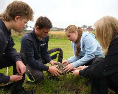 Elever sitter og sjekker jorda