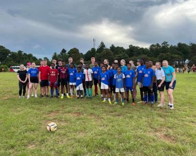 Fotballlag oppstilt, Tomb-elever og lokale barn.