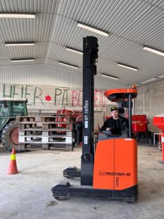 Elev sitter på en orange truck innendørs. 