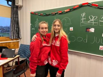 To jenter holder rundt hverandre og smiler til camera.