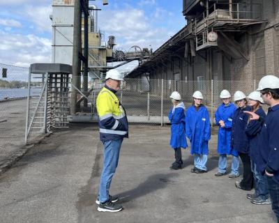 Elever og en omviser utenfor et fabrikkanlegg.