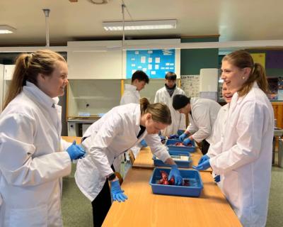 Elever og lærer i hvite frakker gjør eksperiment i et klasserom.