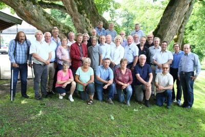 Kvinner og menn ved et tre i parken en sommerdag.